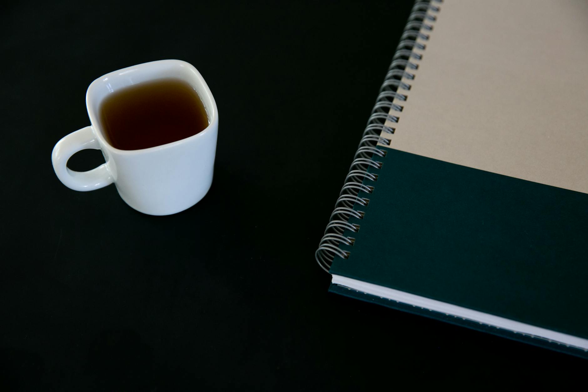 A person sitting peacefully at a clean desk with tea and a phone showing a simple, uncluttered interface — serene morning