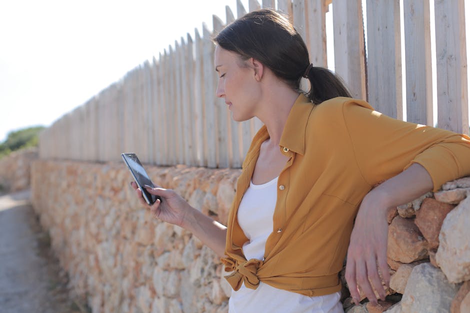 A person sitting outdoors looking at their phone in warm afternoon light, looking relaxed