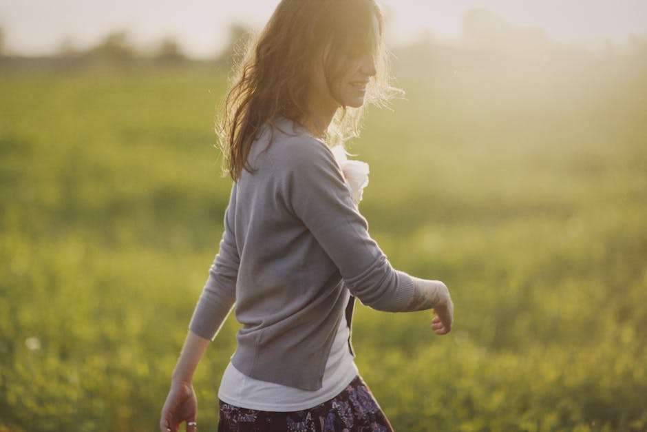 A person smiling while walking outside in the morning sun, looking light and unburdened