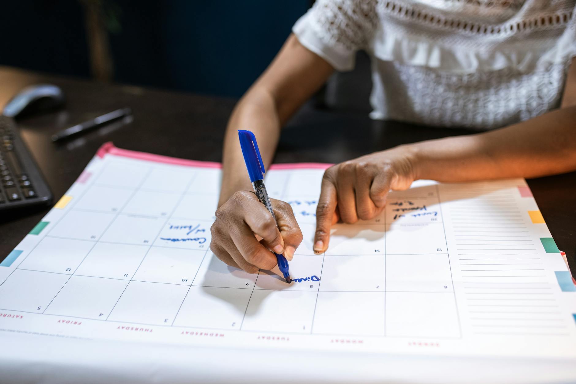 A clean monthly calendar on a wooden desk with a few dates gently circled in ink, a pen resting beside it