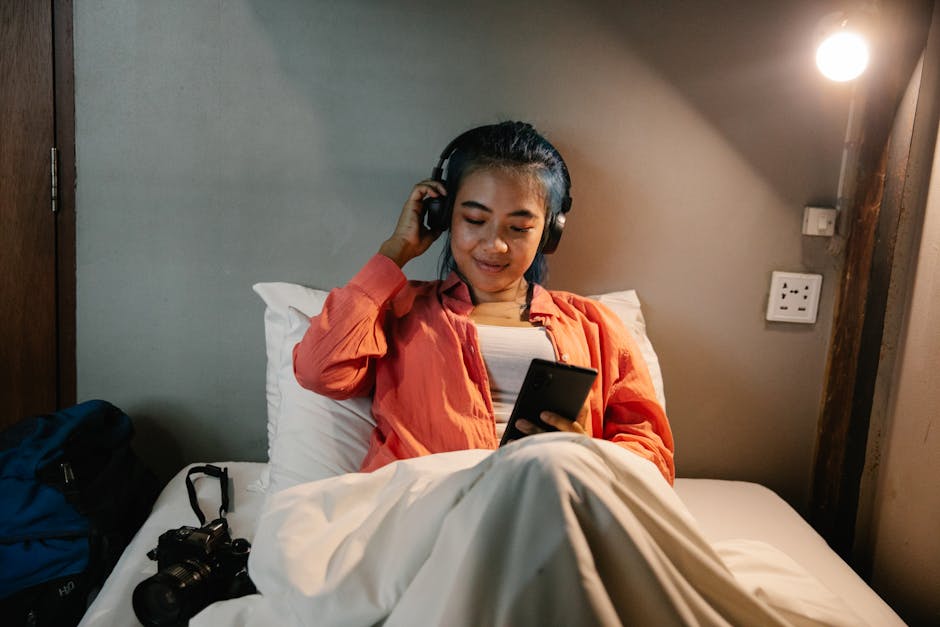 A person relaxing at home on a couch in the evening with a book, warm lighting, and no phone in sight
