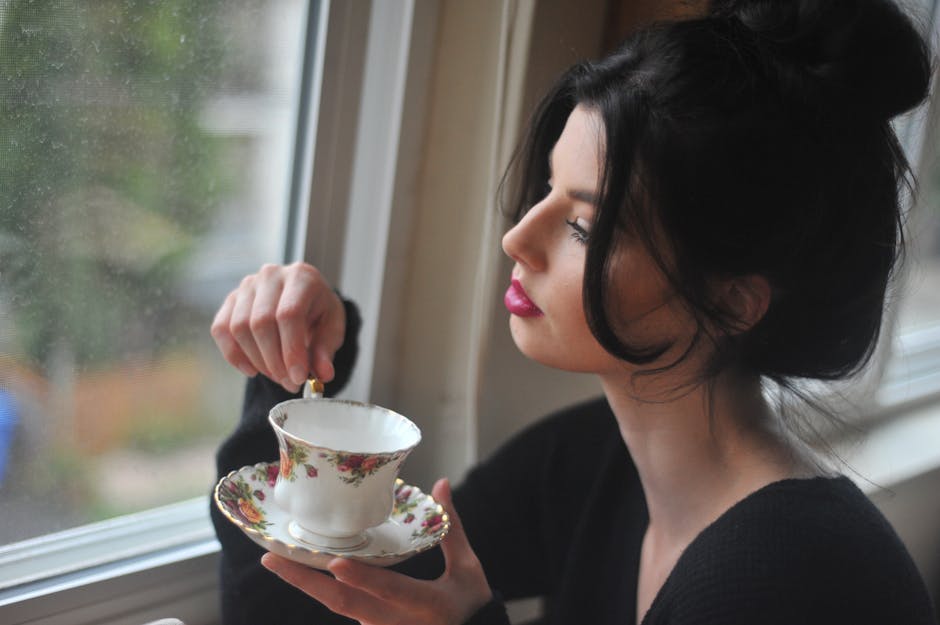 A person sitting by a window with a cup of tea, looking relaxed and unhurried — no screens in sight