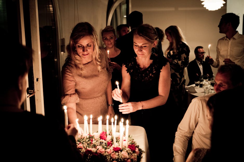 Four people laughing around a candlelit dinner table with wine glasses and simple place settings