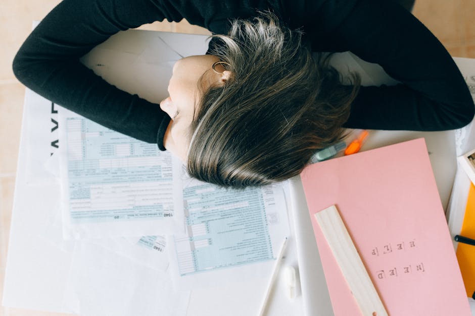 A person overwhelmed at a paper-covered desk