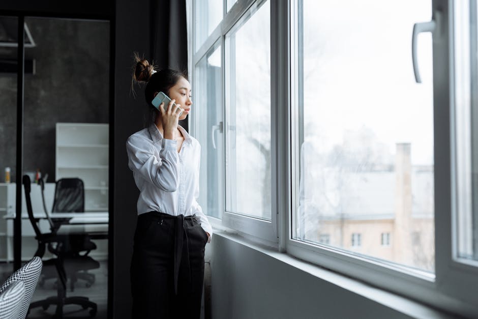 A person glancing at their phone in warm morning window light, soft expression