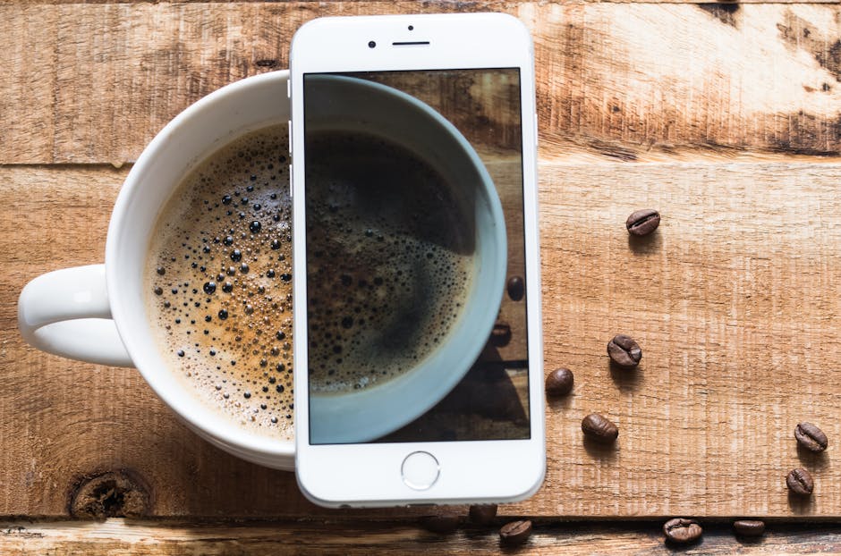 An iPhone resting on a table next to a cup of coffee — simple and familiar
