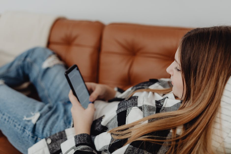 A person relaxing on the couch, phone in hand, casually planning the weekend ahead
