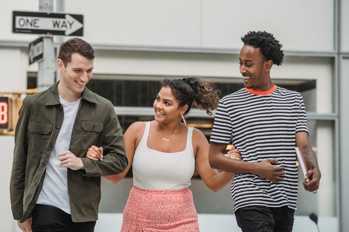 Three diverse friends walking arm-in-arm through the city, laughing and enjoying the moment