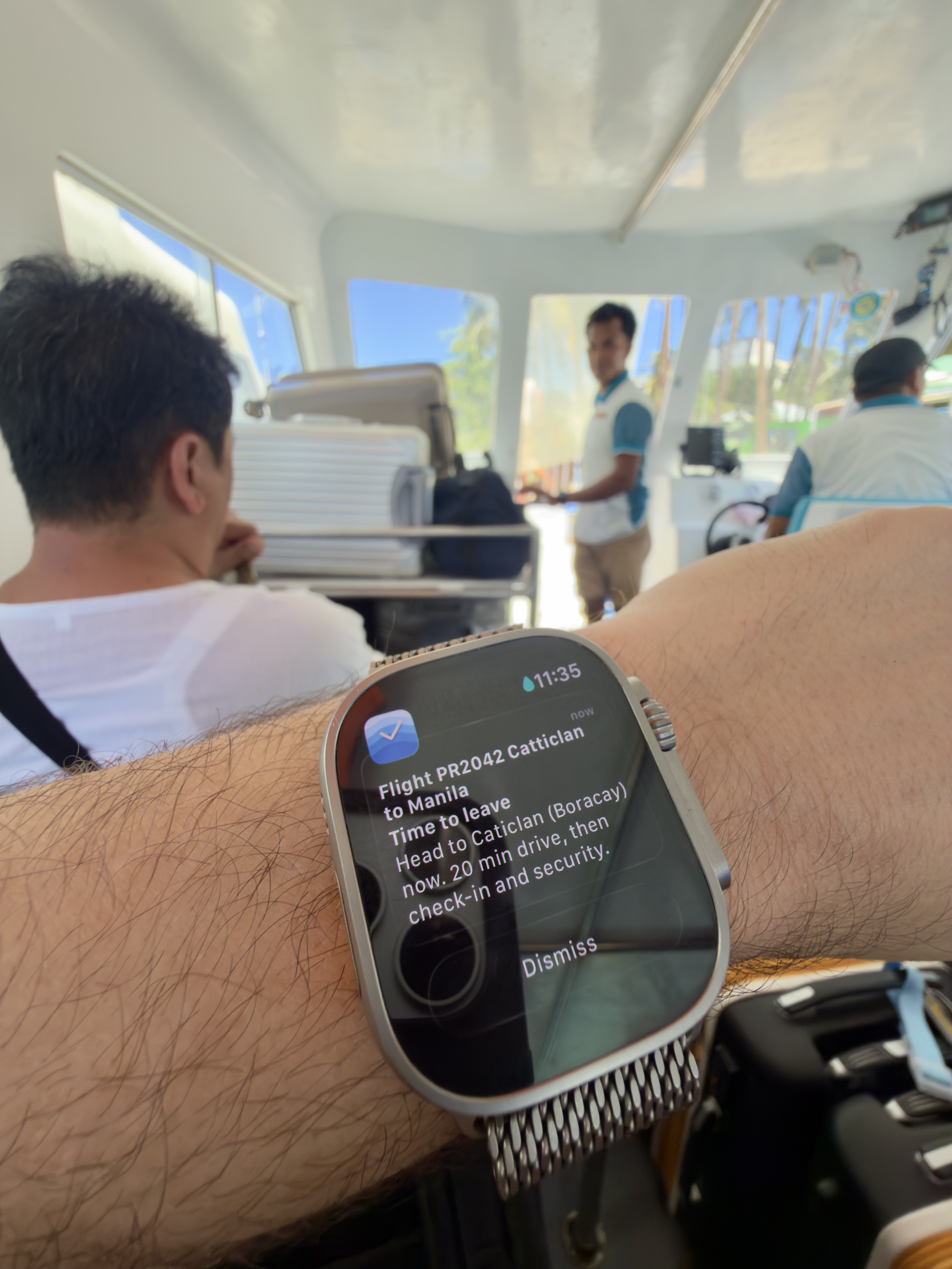 Apple Watch showing Composed flight notification: Flight PR2042 Catticlan to Manila — time to leave, head to Caticlan (Boracay) now, 20 min drive, then check-in and security